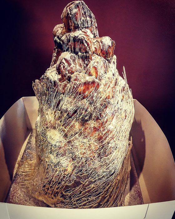 A tall croquembouche wrapped in threads of spun sugar, dusted with icing sugar.