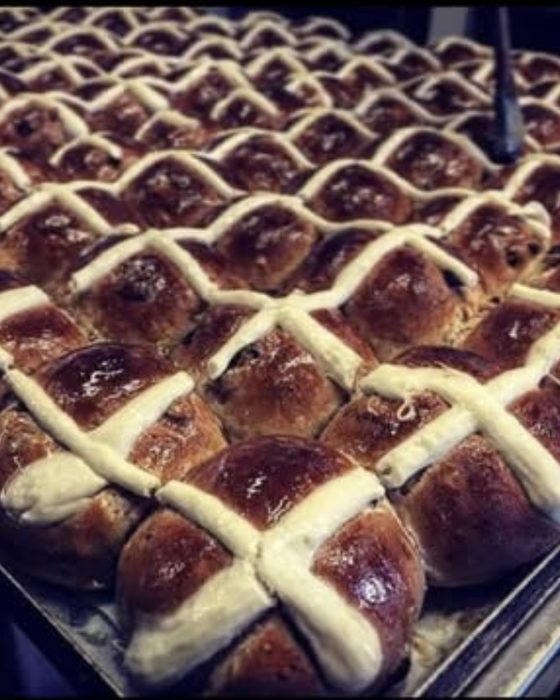 A full tray of glazed hot cross buns fresh from the oven.
